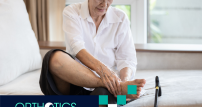 An elderly person sitting on a bed holding her foot