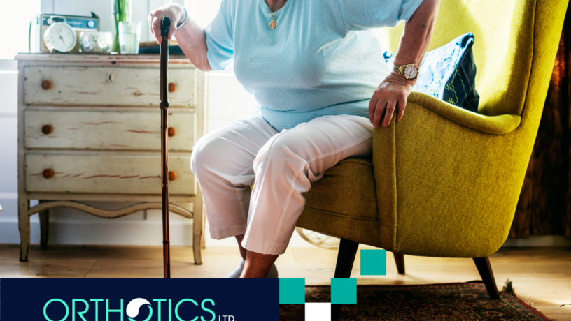An elderly woman standing up using a cane